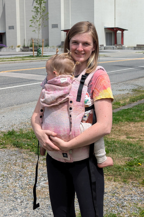 Sarah Labou carrying child in buckle carrier on her front, Learn Babywearing